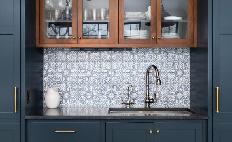 A custom wet bar with blue cabinets and a patterned tile backsplash installed by Smucker & Sons Inc in Ephrata, PA.