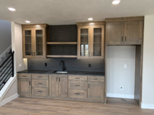 Custom wet bar installation with wooden cabinets and dark tile backsplash by ELS Construction in Springfield, MO.