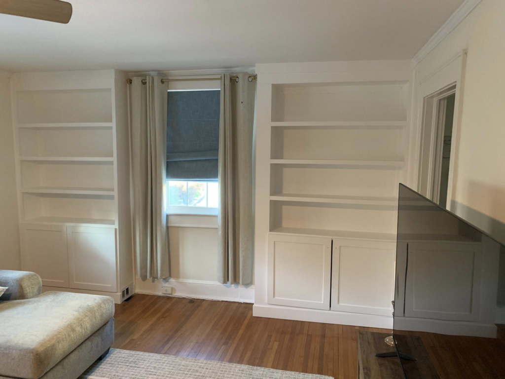 Custom white built-in bookshelves installed around a window by Carolina Handyman Builder in Taylors, SC.