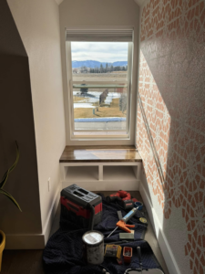 A newly installed custom window bench with storage shelves, surrounded by handyman tools, by JP Handyman Wyo in Sheridan, WY