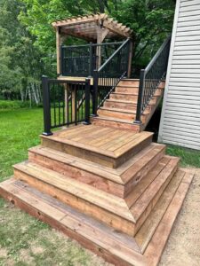 A newly constructed custom wood deck and stairs with black railings, built by Orion Construction Services in Duluth, MN.