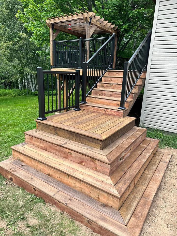 A newly constructed custom wood deck and stairs with black railings, built by Orion Construction Services in Duluth, MN.