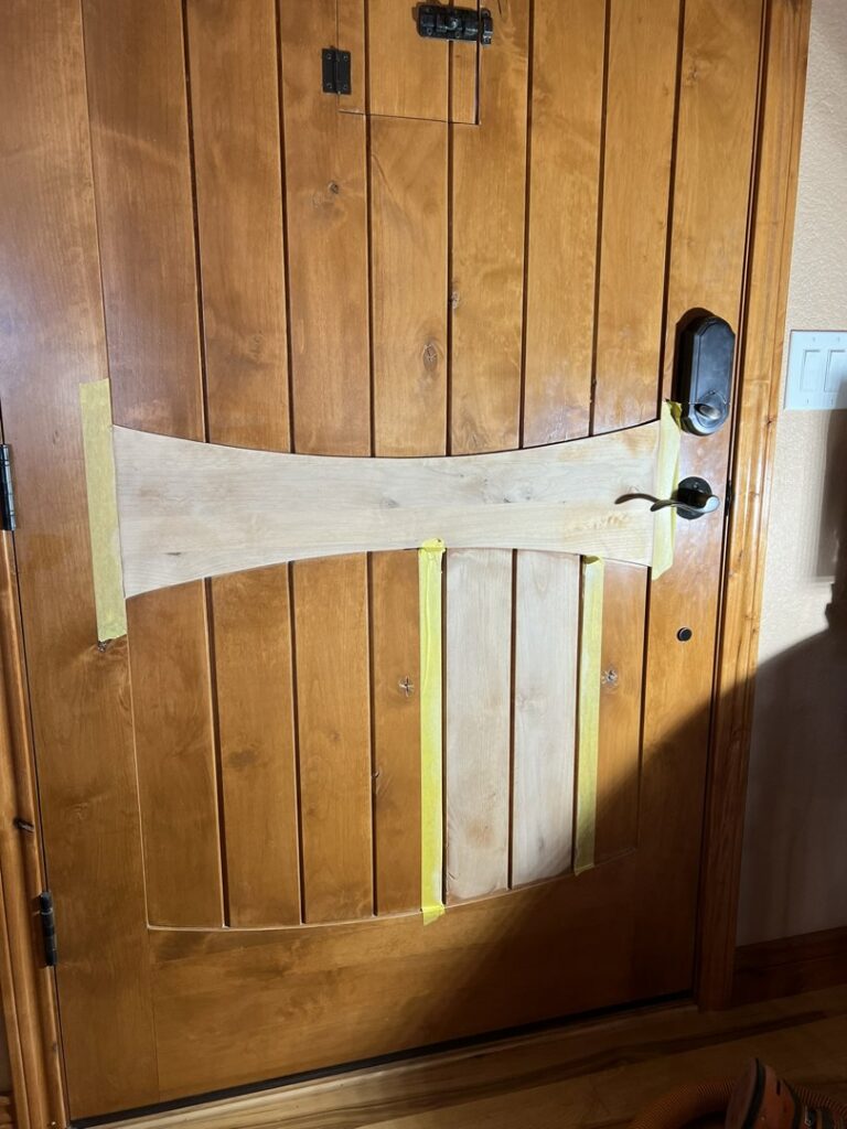 A wooden door with a custom wood panel taped for modification by High Plains Craftsmen in Cheyenne, WY.