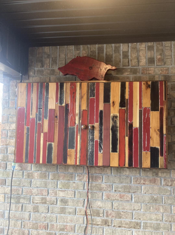 A custom-built rustic wood TV cabinet installed on a brick wall by HandyMan of NWA in Rogers, AR