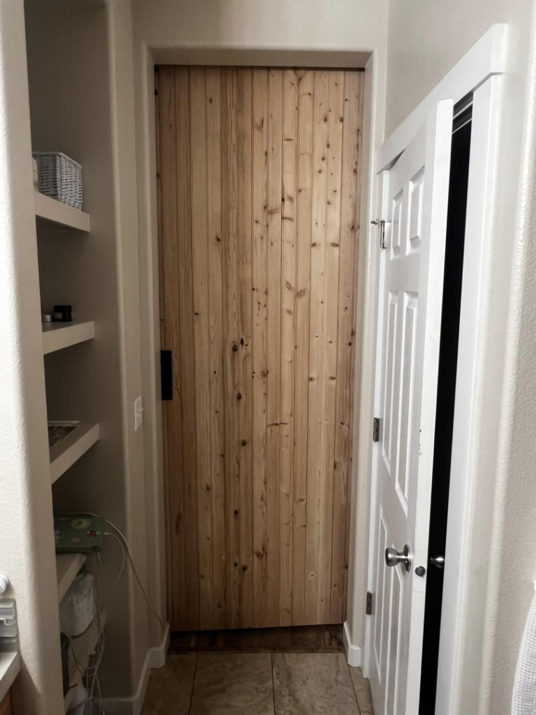 A custom wooden barn door expertly installed by E&D Lozano Handyman in a hallway in Caldwell, ID.