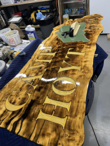 A custom wooden "CABIN HOME" sign crafted by J & J Custom Builders LLC in Milford, CT, showcasing their woodworking skills.