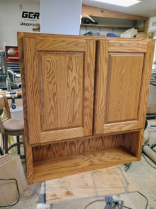 Exterior of a newly installed custom wooden cabinet with an open shelf by The Cowboy Carpenter Handyman Service LLC in Bismarck, ND.