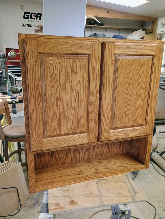 Exterior of a newly installed custom wooden cabinet with an open shelf by The Cowboy Carpenter Handyman Service LLC in Bismarck, ND.