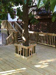 A unique custom wooden deck expertly built around a tree by Fence Me In And Decks Too in Glen Allen, VA.