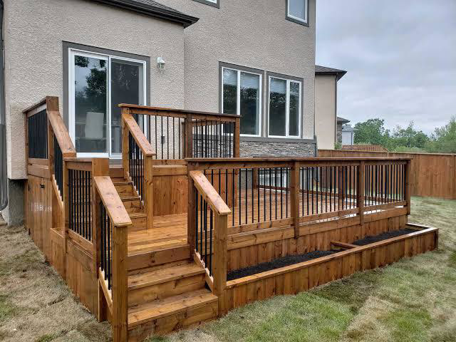A custom wooden deck with stairs and black railings installed by Pineda's Construction LLC in Colorado Springs, CO