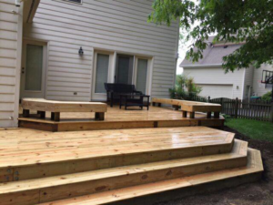A custom-built wooden deck with integrated steps and benches by Fence Me In And Decks Too in Glen Allen, VA.