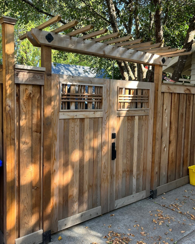 A custom-built wooden fence and gate with a decorative pergola-style top by PNW Home Improvements, LLC in Portland, OR