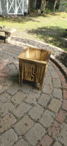 A custom-built wooden planter box sitting on a brick patio, crafted by Turn Key Of Charleston in North Charleston, SC.