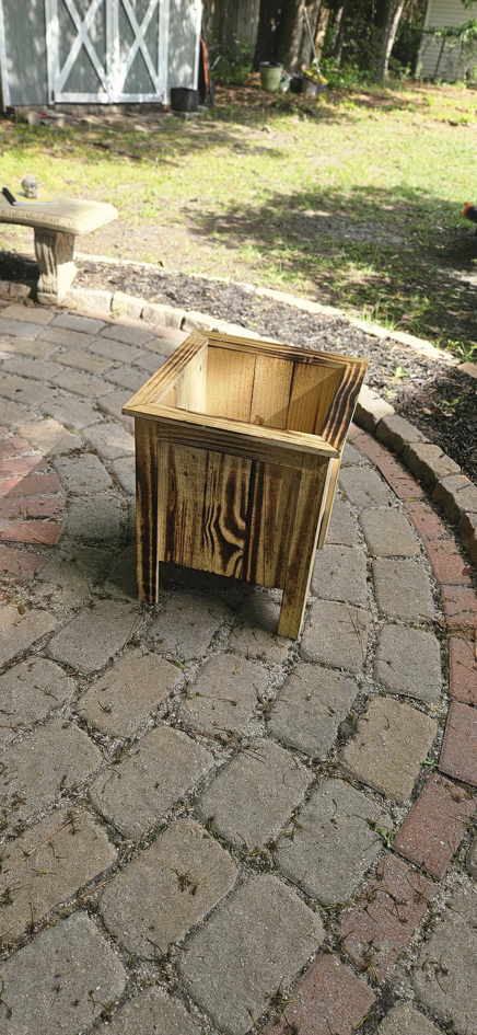 A custom-built wooden planter box on a paved patio, crafted by Turn Key Of Charleston in North Charleston, SC.