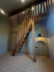 A custom-built wooden staircase leading to a cozy loft area, part of a home remodel by H4 Construction and Remodeling in Blue Springs, MO.