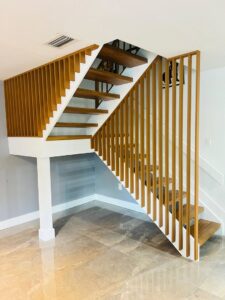 A custom wooden staircase with open risers and vertical slat railings, a project completed by SD Masters in Miami, FL.