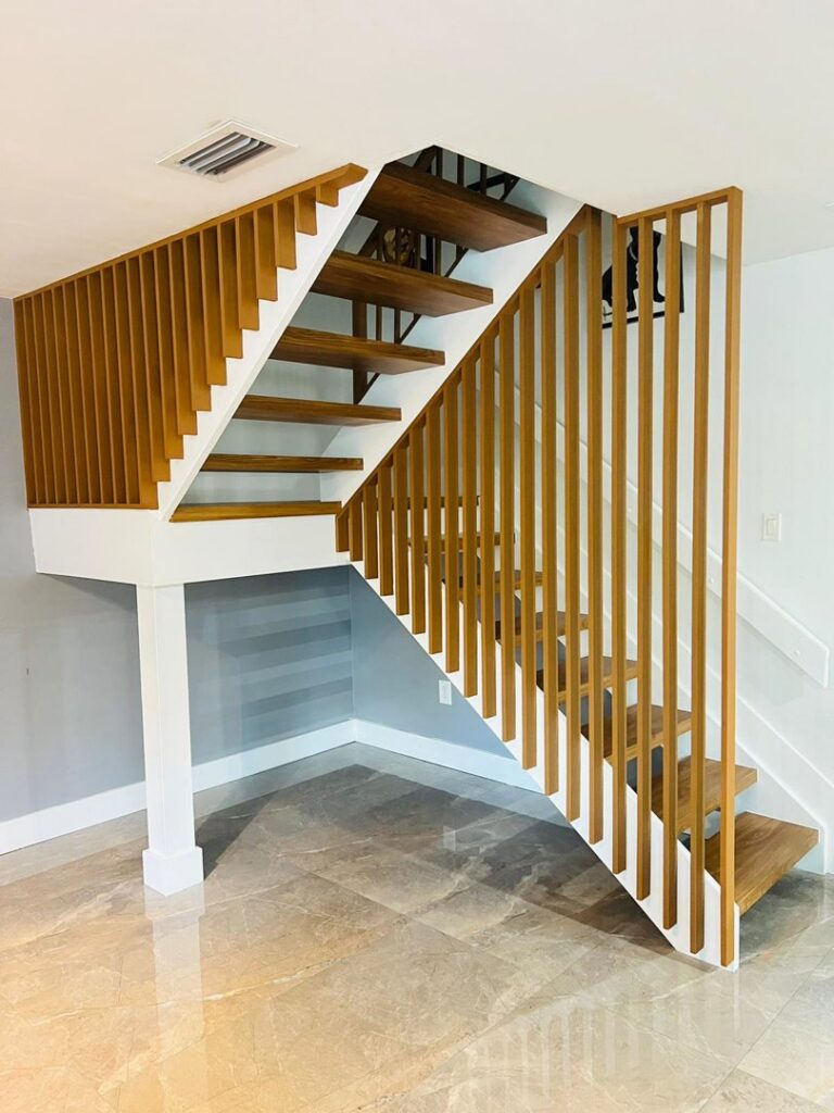 A custom wooden staircase with open risers and vertical slat railings, a project completed by SD Masters in Miami, FL.