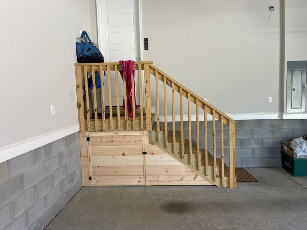 Custom wooden staircase with built-in storage in a garage by Total Garage Works in Indian Trail, NC.