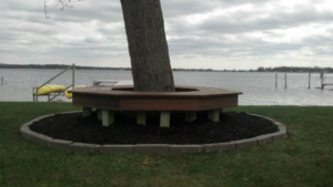 A custom-built hexagonal wooden bench installed around a tree by Cutler Builders in Caledonia, MI.