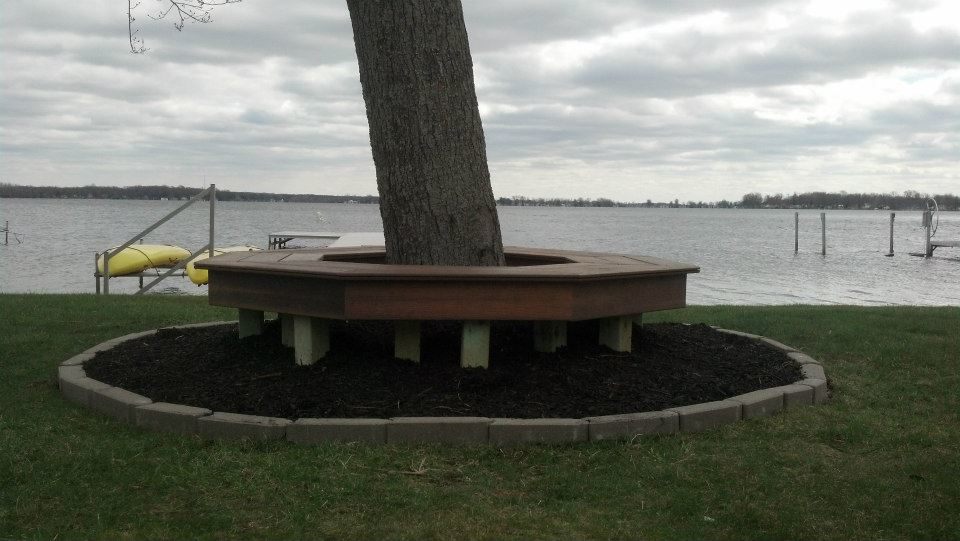 A custom-built hexagonal wooden bench installed around a tree by Cutler Builders in Caledonia, MI.
