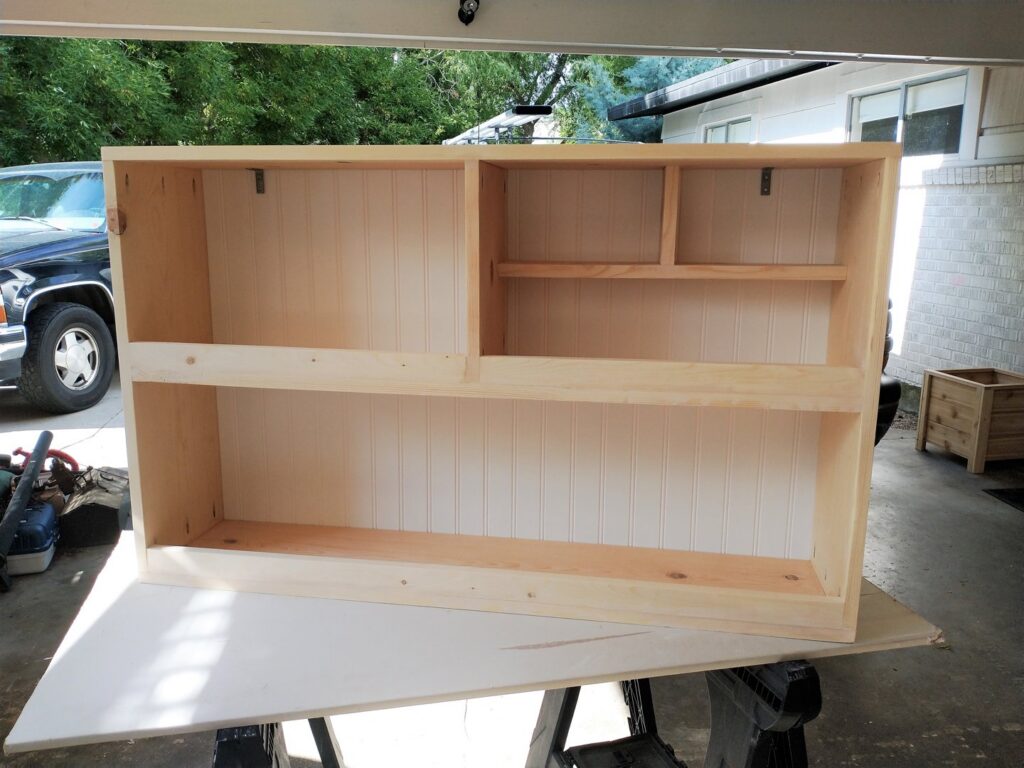An unfinished custom-built wooden wall cabinet with shelves, crafted by Boise Handyman & Remodel in Boise, ID.