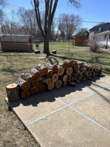 Neatly stacked cut logs and firewood on a patio, ready for removal after tree service by ArborMaster Tree Service Sioux Falls SD.