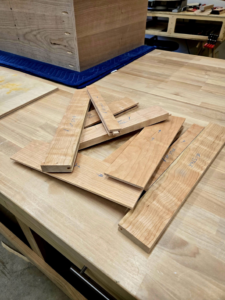 Various cut pieces of wood, prepared for cabinetry or furniture, on a workbench by Kingsbury Builders LLC in Janesville, WI