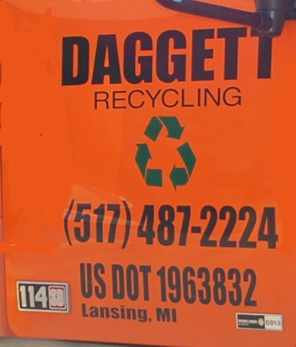Close-up of the side of a Daggett Container Service LLC truck showing 'DAGGETT RECYCLING' and contact info in Lansing, MI.