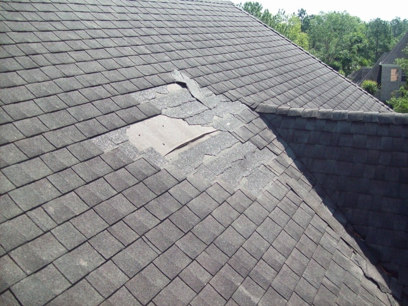 Damaged asphalt shingle roof with missing shingles, showing a clear need for repair by Castle Contracting Group in Cincinnati, OH.