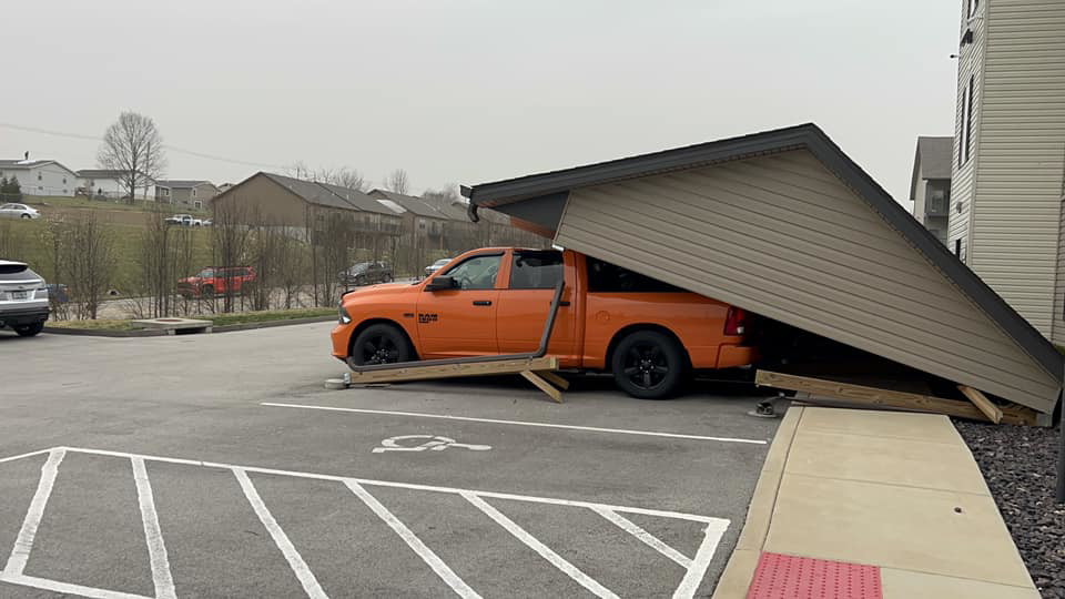 An orange truck partially covered by a damaged and collapsed carport structure, needing repair from Larson Exteriors in Sunset Hills, MO.