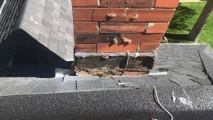 Damaged chimney flashing on a shingle roof, showing a repair need by Elite Roofing Colorado Springs, CO.