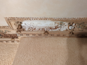 Close-up of damaged decorative crown molding with peeling paint, showing restoration needs by Imagine Painting and Restoration Services in Fort Collins, CO.