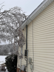 Damaged exterior electrical conduit and siding on a house, indicating storm repair work by HHS Contractors in Providence Village, TX.