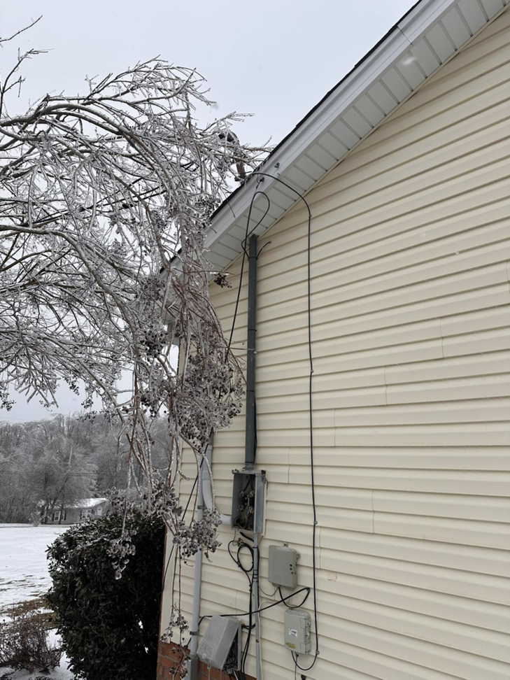 Damaged exterior electrical conduit and siding on a house, indicating storm repair work by HHS Contractors in Providence Village, TX.