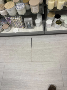 Damaged floor tiles with a noticeable gap, indicating a need for floor repair services from Byrd Property Restoration, LLC in Parkersburg, WV.