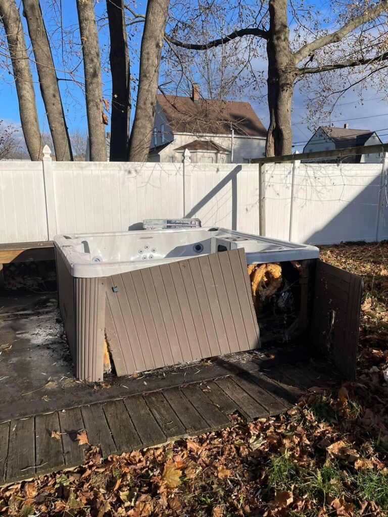 A damaged hot tub in a backyard, awaiting professional hot tub removal service from Tj's junk removal LLC in Derry, NH.