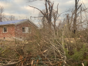 A damaged brick house with a blue tarp on the roof, ready for restoration by Azure Construction in Clarksville, TN