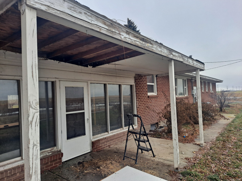 A damaged patio cover with a collapsed section and peeling paint, before repair by Honey Don'ts Handyman Service in Twin Falls, ID.