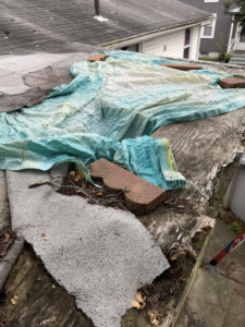 A damaged roof with exposed wood and old shingles, showing a project before repair by Kznconstructionllc in Johnston, RI.