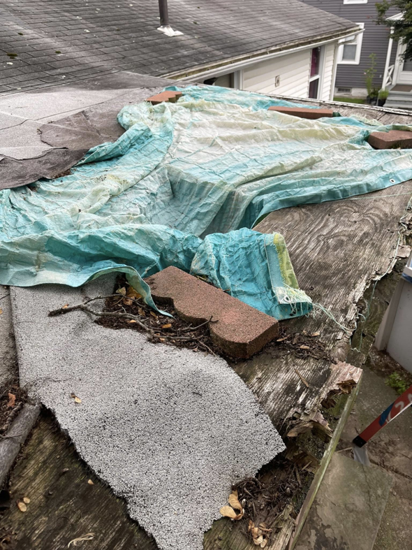 A damaged roof with exposed wood and old shingles, showing a project before repair by Kznconstructionllc in Johnston, RI.