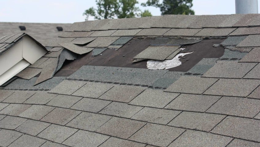 Close-up of a damaged roof with missing and torn shingles, indicating the need for repair by The Roof Guy in Fort Lauderdale, FL.
