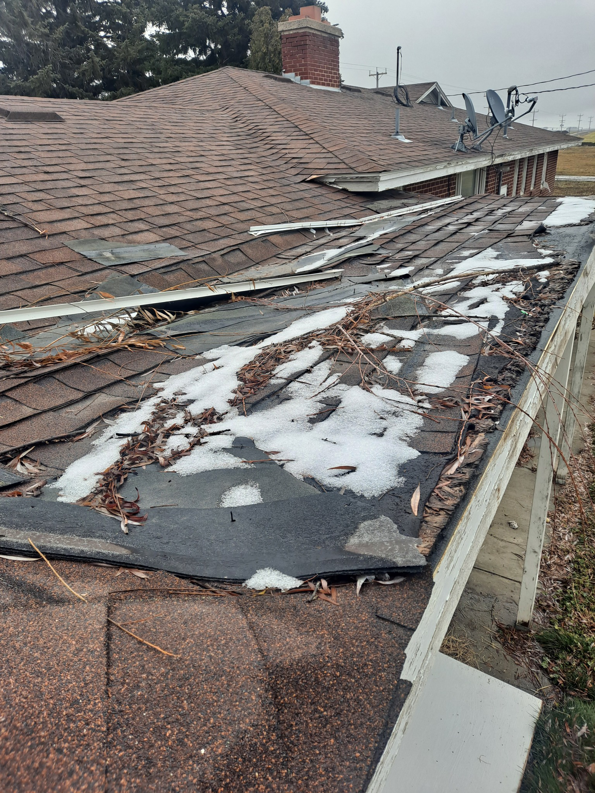 A damaged roof with missing shingles and snow, indicating a repair job by Honey Don'ts Handyman Service in Twin Falls, ID.