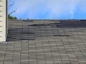 A residential shingle roof with significant damage, including missing and curled shingles, needing repair by BLC Roofing in Akron, OH