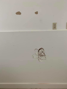 A damaged wall with holes and peeling paint, showing the need for drywall repair by Hey Matt in Sheridan, WY