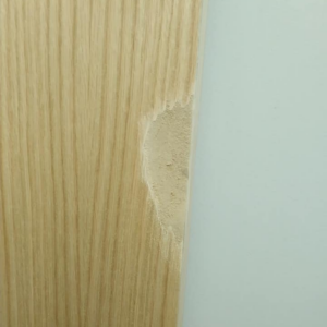 Close-up of a chipped wooden door or panel edge needing repair by Bevard Enterprises in Millcreek, UT.