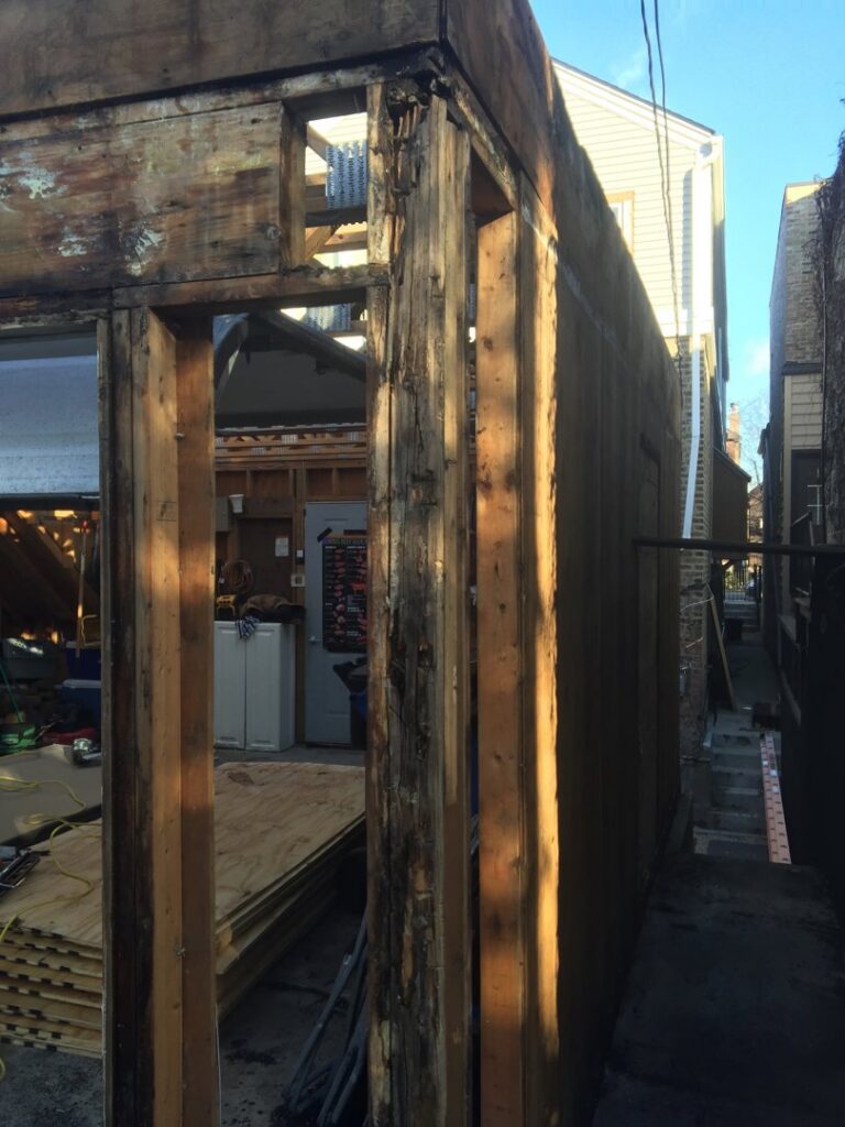 Close-up of damaged wood framing on an old structure, indicating a need for repair by A-Windy City Garages & Doors in Chicago, IL.