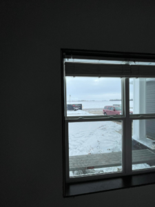 Handyman repairing damaged wood and insulation on a structure by Next Level Builders, Inc. in Grand Forks, ND.