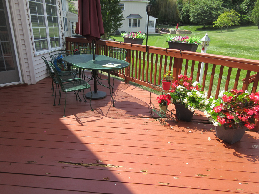 A worn wooden deck with peeling paint and damaged boards, indicating a need for repair by Sundecks, Inc. in Manassas, VA.