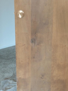 A wooden door with a brass doorknob showing a dark discolored spot, ready for repair by Bevard Enterprises in Millcreek, UT.