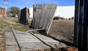 A severely damaged wooden fence requiring repair or replacement by A/M Fence in Norman, OK